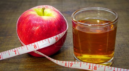 Foto de Vinagre de manzana, zumo de manzana y manzana con cinta métrica. comida saludable, bebida para el control de peso en verano. Ideas de salud para bajar de peso. - Imagen libre de derechos