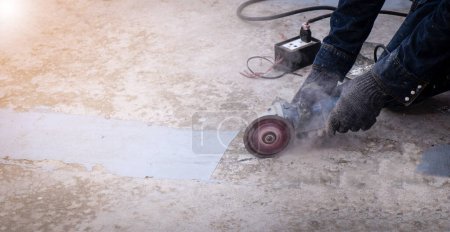 Téléchargez les photos : Les travailleurs utilisent des meuleuses industrielles pour réparer les fissures du plancher. Réparation plancher de pont imperméabilisation - en image libre de droit