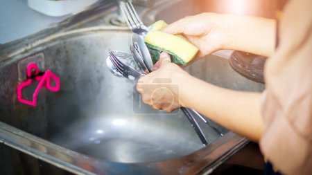 Photo for Woman washing spoons and forks in the kitchen close-up - Royalty Free Image