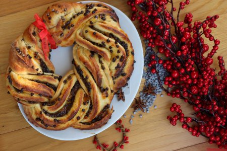 Chocolate and orange jam braided Brioche bread with one slice on a plate on wooden table with Christmas decoration