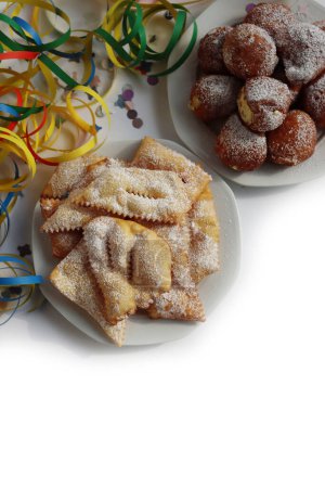 Traditionelle italienische Crostoli (auch Chiacchere, Frappe, Bugie, Cenci, Galani genannt) und Frittelle mit Sahne auf weißem Hintergrund mit Konfetti und bunten Karnevalsdekorationen