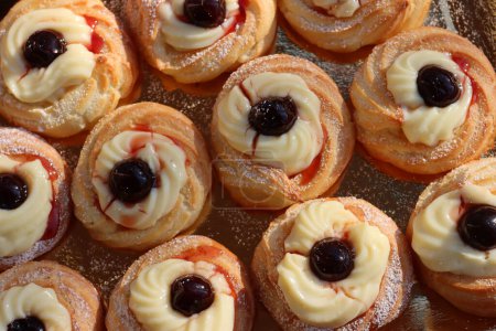 Italian traditional fried Zeppole pattern for St. Joseph (Fathers day). Homemade sweet pastry with custard cream and black cherries 