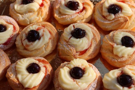 Italian traditional fried Zeppole pattern for St. Joseph (Fathers day). Homemade sweet pastry with custard cream and black cherries 