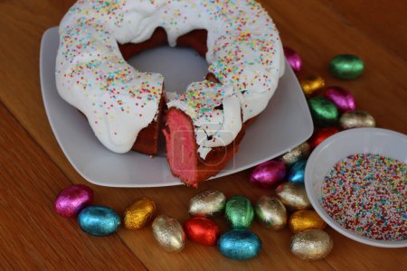 Ciaramicola mit einer Scheibe schneiden. Traditionelle umbrische Torte zu Ostern. Roter Donut-Kuchen, mit Alchermes und mit weißer Zuckerglasur und Streusel dekoriert