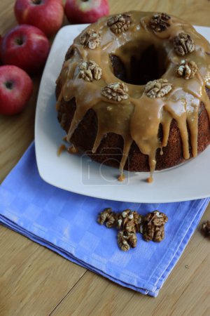 Photo for Apple and Walnut Bundt Cake with caramel glaze on a plate on wooden table - Royalty Free Image