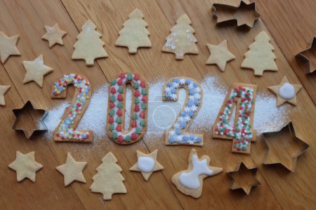Foto de Galletas de corteza corta con salpicaduras de colores en forma de números 2024 withcokies en forma de árbol y estrellas en la mesa de madera - Imagen libre de derechos