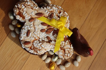 Colomba Pasquale. Sweet Easter cake with dark chocolate hen and eggs wrapped in foil. Italian traditional pastry on wooden table