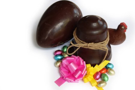 Easter chocolate bell with chocolate eggs, chocolate chicken and pink and yellow bows isolated on white background 