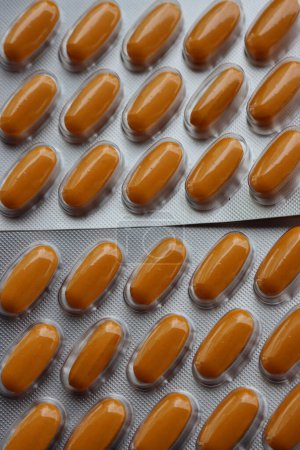 Pharmaceutical medicine capsules on wooden table. Orange pills in blister packaging