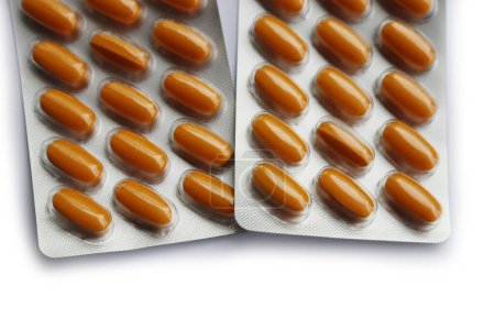 Pharmaceutical medicine capsules isolated on white background. Orange pills in blister packaging