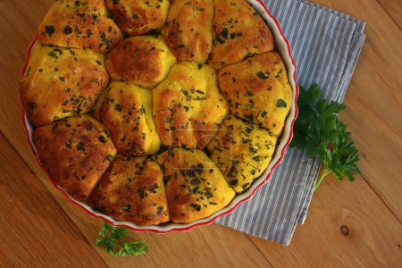 Kurkuma und Petersilienbrot. Gesundes Kurkuma-Brot in der Kuchenform auf einer grau gestreiften Serviette auf Holztisch