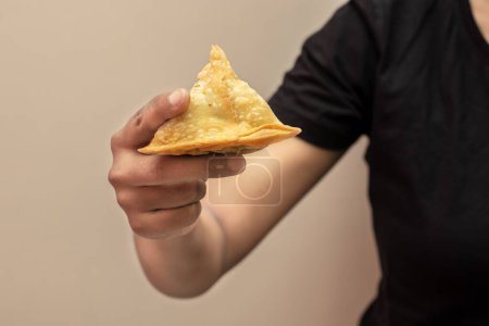 Photo for A lady holding Indian snack Samosa. Selective focus. - Royalty Free Image