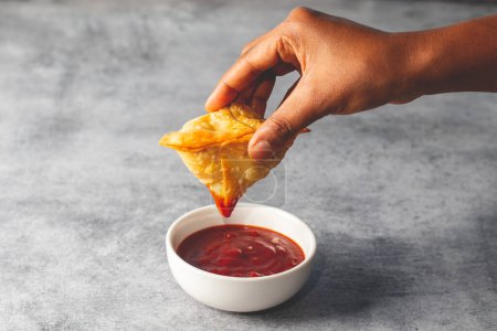 Photo for A lady dipping Samosa on tomato sauce. Indian street food. - Royalty Free Image