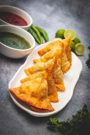 selective focus Samosa, Spiced potato-filled pastry, crispy, Savory, popular Indian snack with tomato and mint chutney. 