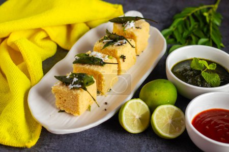 Selective focus of popular Gujrati food Dhokla with mint chutney and black background. 