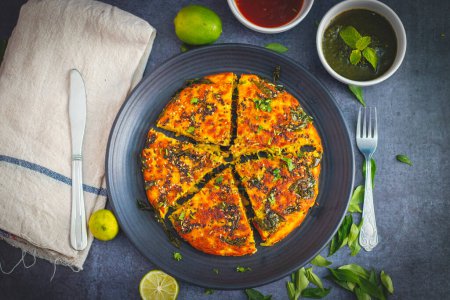 enfoque selectivo de Gujrati plato handvo corte tringle rebanada decorado con limón, hojas de curry, chutney menta y salsa de tomate.