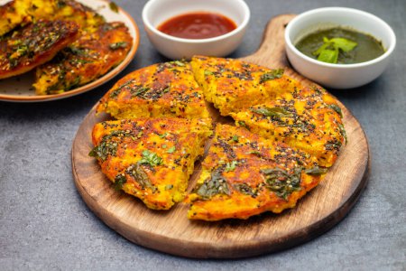 selective focus of famous Gujrati dish Handvo with mint chutney and tomato sauce. Spiced lentil cake from India. 