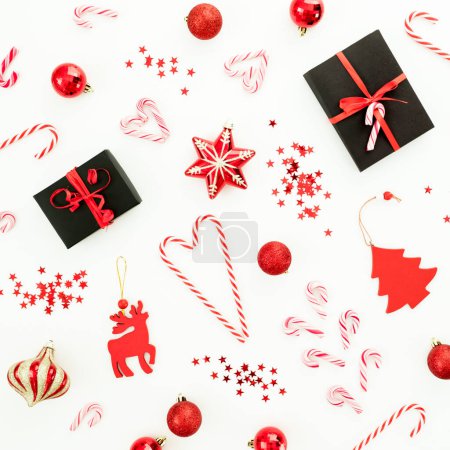 Foto de Composición navideña con regalos, decoración, juguetes, bastones de caramelo y confeti sobre blanco. Puesta plana - Imagen libre de derechos
