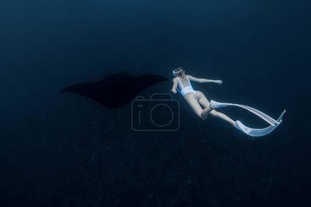 Téléchargez les photos : Femme plongeur libre avec des nageoires blanches nager avec raie manta. Plongée libre avec grand raie manta - en image libre de droit