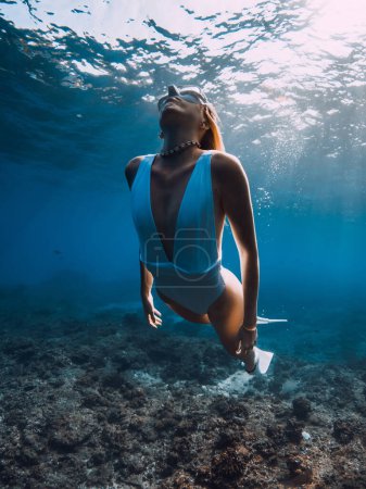 Téléchargez les photos : Femme plongeur libre glisse avec des nageoires sur les coraux. Plongée libre et belle lumière du soleil dans l'océan bleu - en image libre de droit