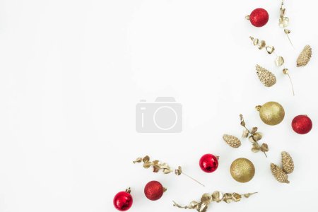Foto de Composición navideña con decoración de árboles dorados y rojos sobre fondo blanco. Piso tendido, vista superior. - Imagen libre de derechos
