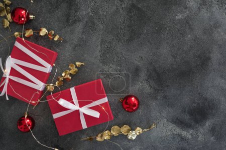 Téléchargez les photos : Composition de Noël avec branches dorées, coffret cadeau, décoration et lumières avec bokeh sur sombre. Pose plate - en image libre de droit