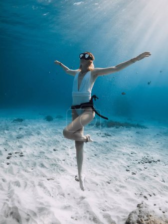 Téléchargez les photos : Belle femme plongeuse libre posant sous l'eau. Plongée libre avec femme dans l'océan bleu avec des rayons de soleil étonnants - en image libre de droit