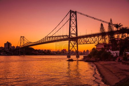 Photo for Hercilio luz cable bridge with warm sunset and reflection on water in Florianopolis - Royalty Free Image