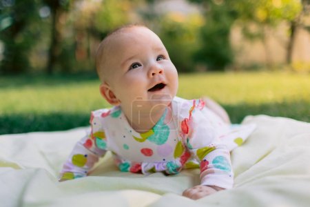 Téléchargez les photos : Bébé fille sourire dans le jardin sur la pelouse - en image libre de droit