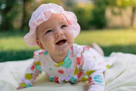 Photo for Smiling baby girl laying in garden on the lawn - Royalty Free Image