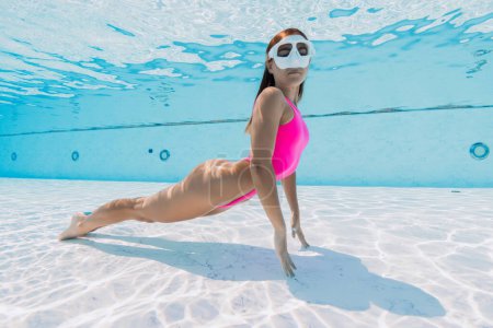 Téléchargez les photos : Sexy jeune femme en bikini lumineux nageant sous l'eau dans la piscine - en image libre de droit