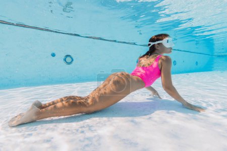 Téléchargez les photos : Femme sexy avec maillot de bain rose posant sous l'eau dans la piscine - en image libre de droit