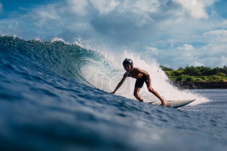 Photo for January 4, 2023. Bali, Indonesia. Young boy in tropical ocean during surfing. Surfer ride on surfboard in barrel wave. - Royalty Free Image