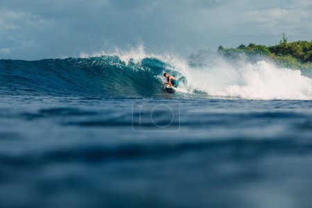 Téléchargez les photos : January 4, 2023. Bali, Indonesia. Teenager in tropical ocean during surfing. Surfer ride on wave. - en image libre de droit