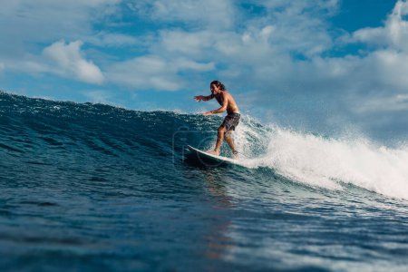 Téléchargez les photos : January 4, 2023. Bali, Indonesia. Man in tropical ocean during surfing. Surfer ride on surfboard on blue wave. - en image libre de droit