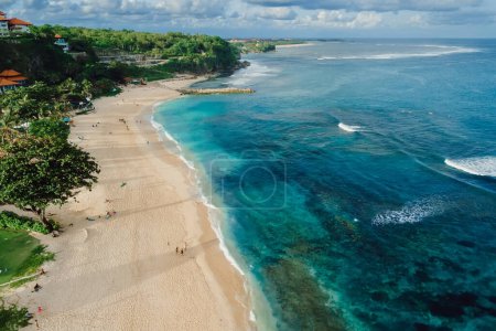 Tropical beach with blue ocean and waves in Bali island. Aerial view