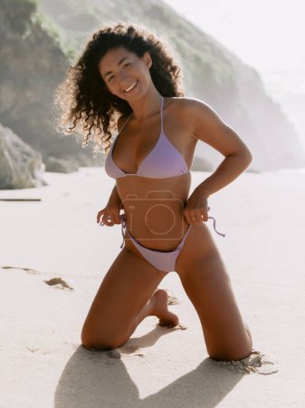 Foto de Attractive smiling woman in bikini with tanned body posing on beach, beautiful model in bikini - Imagen libre de derechos