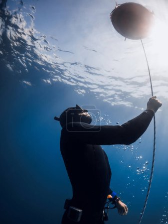 Téléchargez les photos : October 03, 2022. Amed, Indonesia. Men in wetsuit with fins training dive on deep in blue ocean. Professional freediver comes to the surface underwater in transparent sea - en image libre de droit