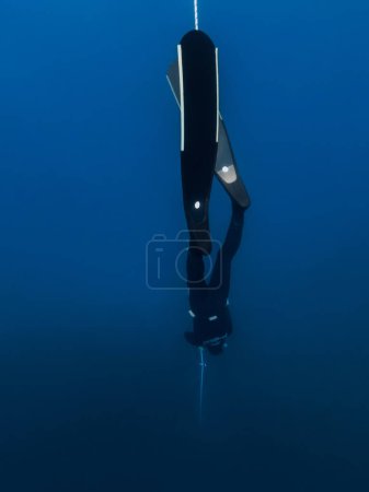 Foto de October 03, 2022. Amed, Indonesia. Freediver in wetsuit with fins training dive on deep in blue ocean. Professional freediving underwater in transparent sea - Imagen libre de derechos