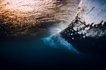 Téléchargez les photos : Barrel wave crash in ocean with sunset or sunrise light. Underwater view of surfing wave - en image libre de droit