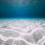 Underwater blue ocean background with sandy sea bottom