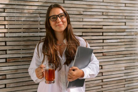 Téléchargez les photos : Attractive young woman with laptop computer and cup of tea - en image libre de droit