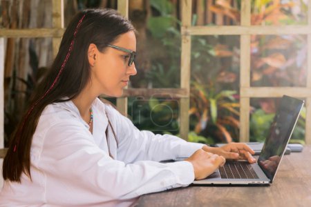 Téléchargez les photos : Attractive young woman typing on laptop computer in summer cafe - en image libre de droit