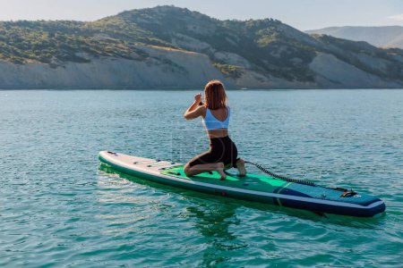Téléchargez les photos : Sexy sporty woman on SUP board in quiet sea with beautiful landscape. - en image libre de droit