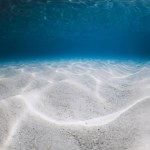 Tropical blue ocean with white sand underwater in Hawaiian island. Ocean texture background