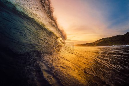 Téléchargez les photos : Perfect barrel wave crashing in ocean on warm sunset or sunrise. - en image libre de droit
