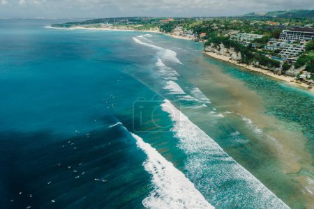 Téléchargez les photos : Ocean with ideal waves and coastline with hotels on Impossibles beach in Bali. Aerial view of tropical island - en image libre de droit