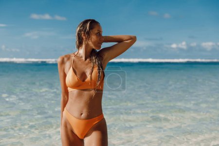 Foto de Portrait of beautiful tanned woman in yellow bikini at ocean beach. - Imagen libre de derechos