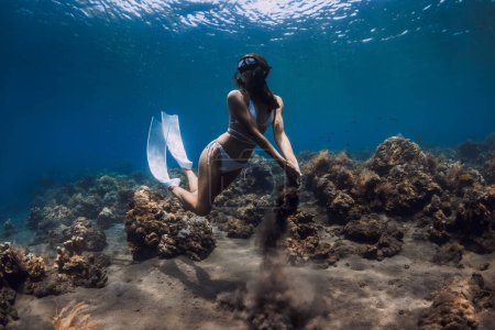 Foto de Mujer liberadora posando con arena en las manos bajo el agua en el océano - Imagen libre de derechos