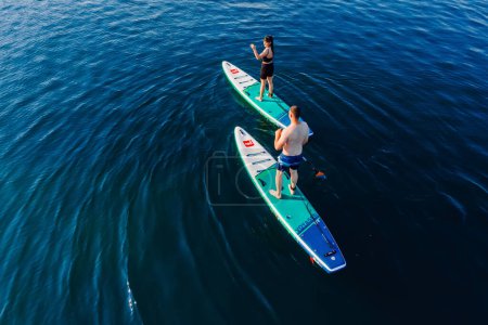 Téléchargez les photos : 24 juillet 2022. Antalya, Turquie. Couple se détendre sur stand up paddle board à la mer bleue. Les gens sur la planche à pagaie rouge dans la mer Méditerranée. Vue aérienne - en image libre de droit